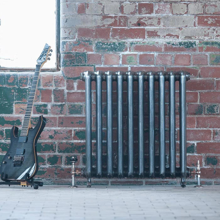 Arroll Duchess 2 Column Cast Iron Radiator, next to a brick wall and a guitar  