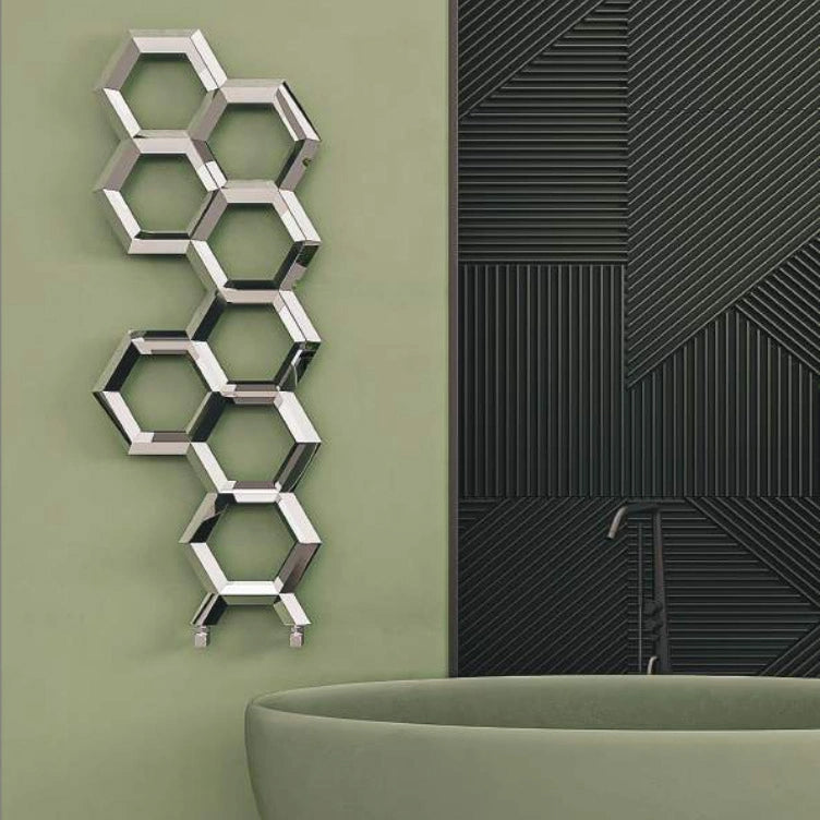 Carisa Alveole Designer Radiator, fixed to a green painted wall next to a green bathtub, in a bathroom space