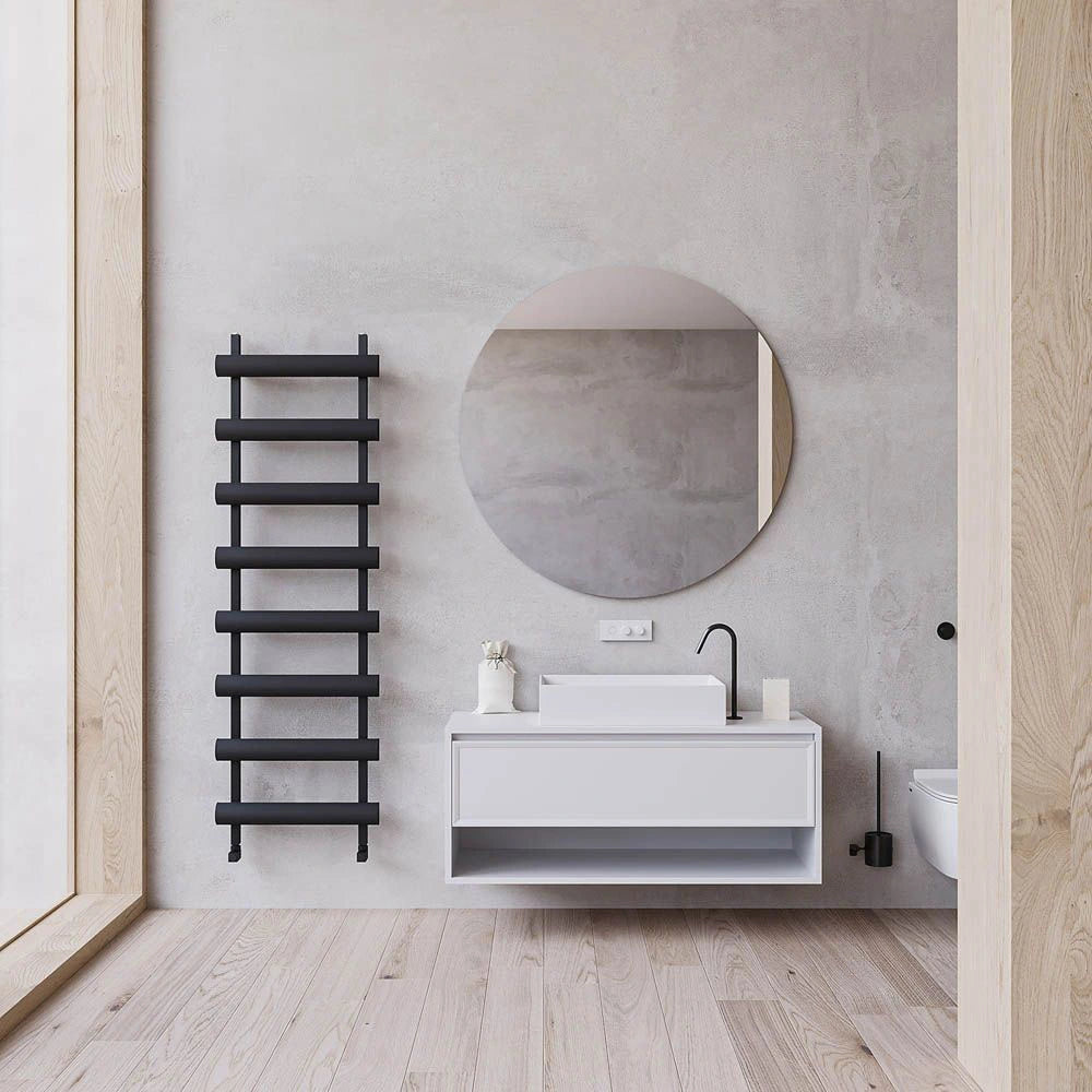 Carisa Moon Aluminium Towel Radiator, in a bathroom space next to a round mirror and basin