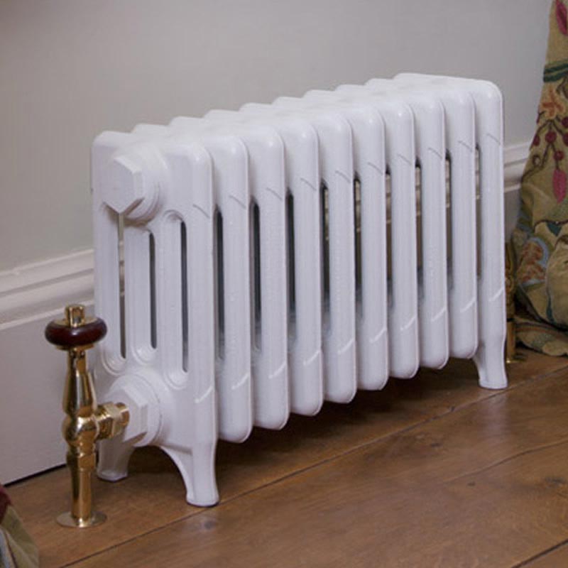 Carron Victorian 4 Column Cast Iron Radiator Special Finishes 460mm Height in a living space hallway, painted white and with brass valves going into the wooden floor boards