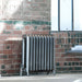 Arroll Princess 2 Column Cast Iron Radiator next to a red brick wall in an interior space