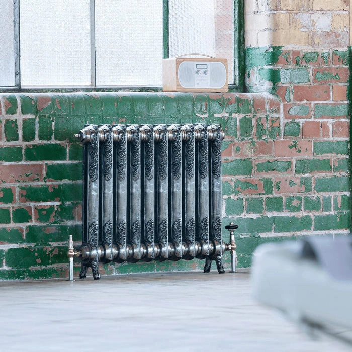 Arroll Rococo 1 Column Cast Iron Radiator next to a brick wall, in a living space