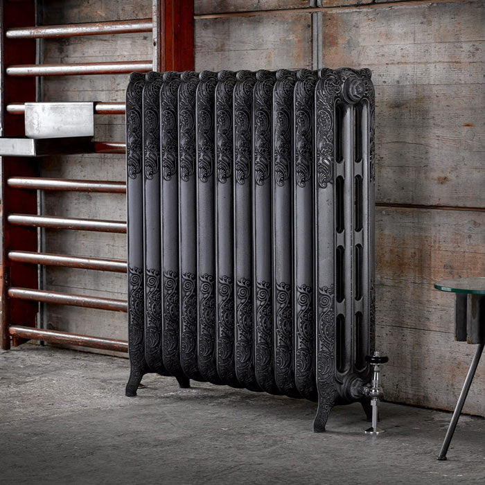 Arroll Rococo 3 Column Cast Iron Radiator, fixed to the floor next to a wooden wall