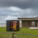 saunum classic sauna for 3 to 4 persons sitting in the backyard of a modern house on the coastline