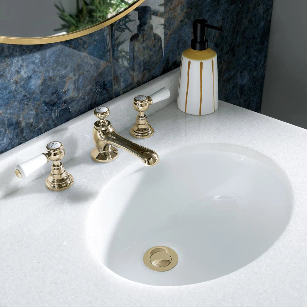 Close up image of white marble top BC Designs Marble basin worktop with polished gold waste and taps with 3 hole basin mixer
